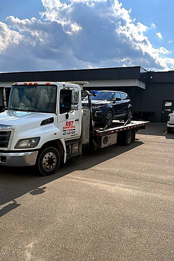 RST flatbed tow truck with an SUV loaded and secured on the deck