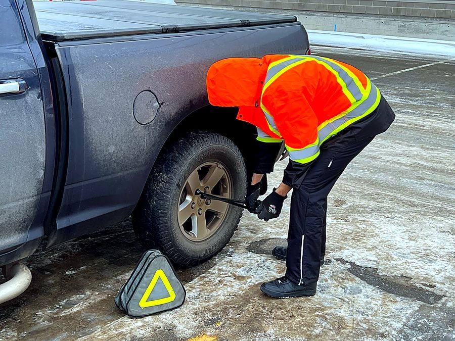 RST roadside technician assisting a driver with a flat tire in Calgary