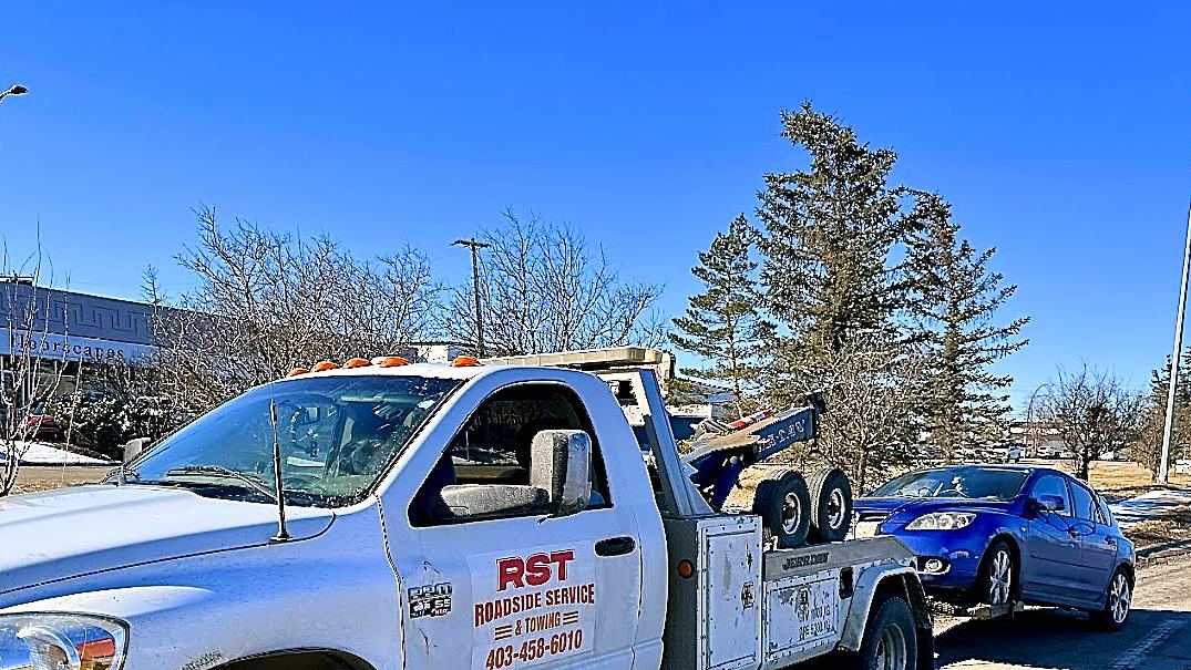 RST wrecker tow truck towing a hatchback in Calgary